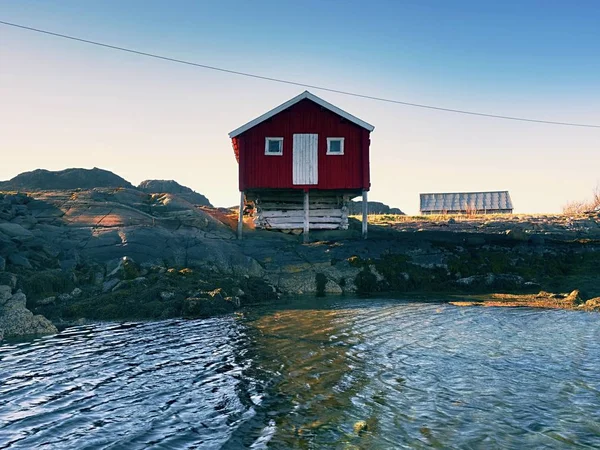 Casa de barco vermelho no cais, ilha rochosa, Noruega. Edifício branco vermelho tradicional no cais perto do mar — Fotografia de Stock