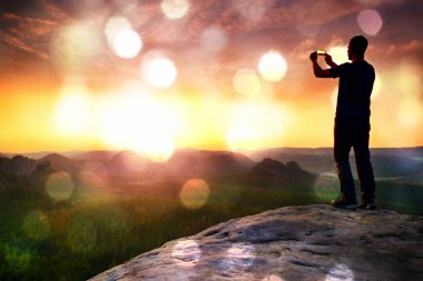 Telefonu el ile uzun boylu backpacker selfie yapar. Güneşli bahar daybreak dağlarda.