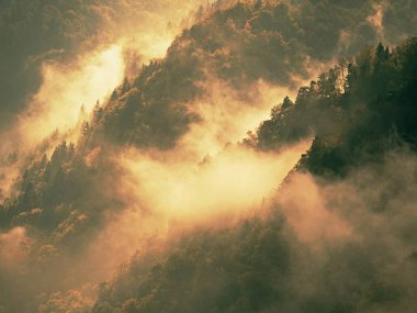 Uzak dağ silsilesi ve derin vadiler yukarıda renkli sis ağır bulutlar