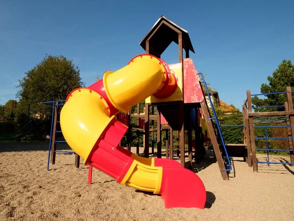 Parque infantil tobogán tubo de colores en el parque público. Nuevo tubo deslizante y escaleras de madera — Foto de Stock