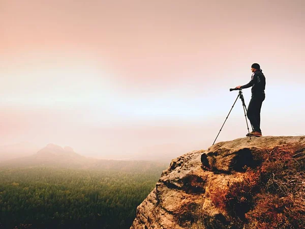 Fotografo d'arte sul posto scatta foto con macchina fotografica sulla cima della roccia. Paesaggio appannato — Foto Stock