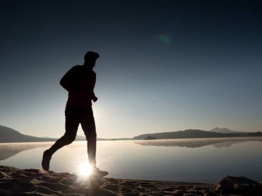 Uzun kumsalda hızlı deniz kıyısında koşan adam uygun. Güçlü runner yaz sabah açık eğitim.