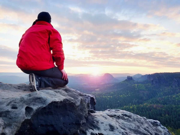Wanderer ruhen sich auf Berggipfel aus. Der Mann lag auf dem Gipfel, unten im Tal. strahlende Morgensonne am Himmel. — Stockfoto