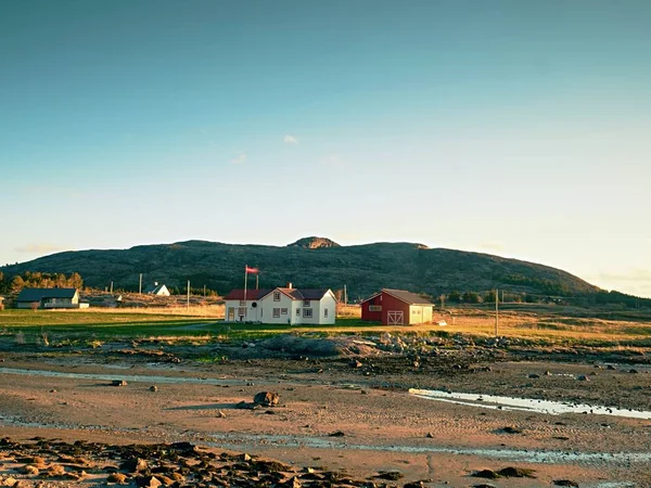 Wioska rybacka. Domki na skalistym wybrzeżu na wyspie. Czerwony biały budynek shinning wiosna promieniami słońca. — Zdjęcie stockowe