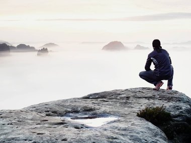 Yalnızlık üzerine maruz kayalık zirve anı. Siyahlı adam muhteşem görünümü keyfini çıkarın. Uzun yürüyüşe çıkan kimse sit tepe üzerinde