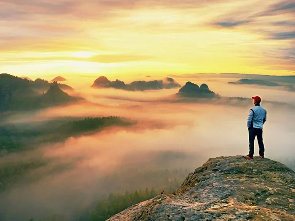 Alleen wandelaar in rode dop op piek van zandsteen rotsen in rock empires park en waakt over de mist staan — Stockfoto