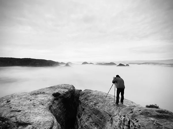 Professional på klippa. Naturfotograf tar bilder med spegel kamera på toppen av rock. Drömmande dimma — Stockfoto