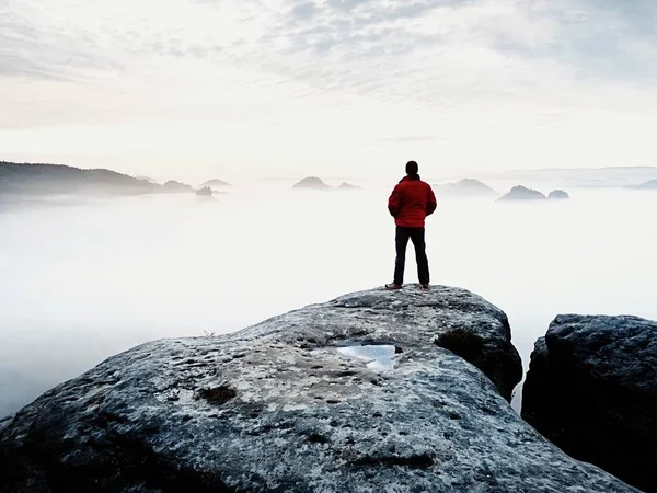 Rückansicht zum Alleinreisenden auf Klippe mit Nebelbalg-Beinen, Sonnenschein am wolkenverhangenen Himmel — Stockfoto