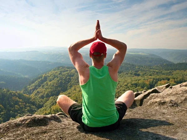 Hombre sentado en la cima de la montaña en pose de yoga. Ejercicio de yoga en el borde con una vista impresionante —  Fotos de Stock