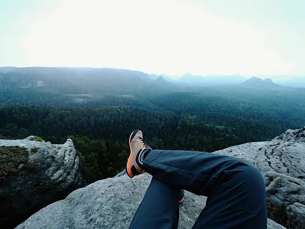 Obosit om drumeție se stabilesc și se bucură de vedere în peisaj peste picioarele sale obosite în cizme turistice — Fotografie, imagine de stoc