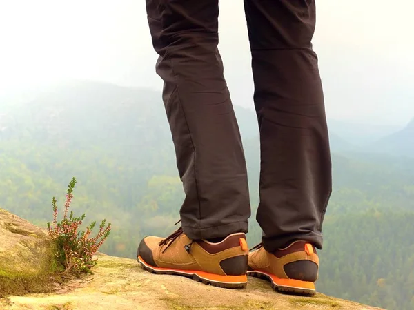 Hiker ben i bekväma trekking stövlar på rock. Man ben i ljus utomhus byxor, läderskor — Stockfoto