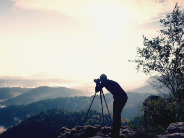 Doğa fotoğrafçısı tripod Zirvesi ve düşünme, kal. Tepelik sisli manzara