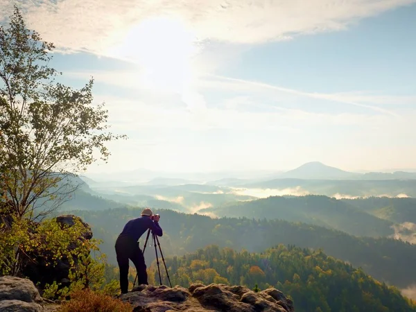 Fotógrafo da natureza ficar no tripé no topo e pensar. Paisagem nebulosa montanhosa — Fotografia de Stock