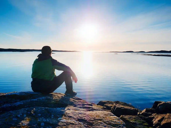 남자는 저녁 바다에 앉아. 등산객 배낭에 해변을 따라 쪼 그리고 앉는 위치에 앉아. — 스톡 사진