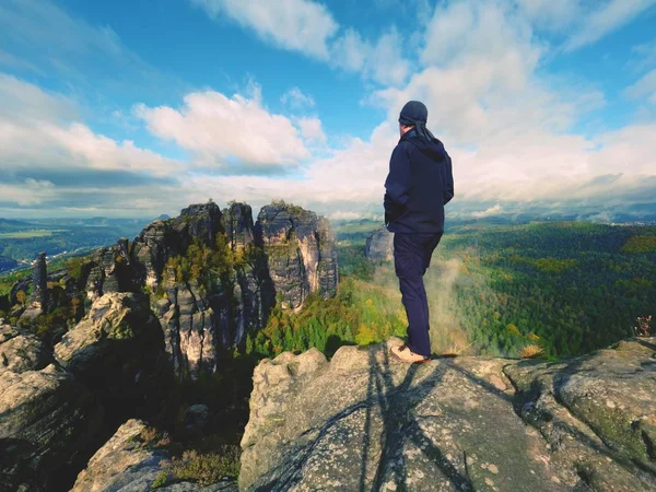 Caminhante em sportswear preto stand no pico da rocha de arenito no parque impérios de rocha e olhando sobre a névoa — Fotografia de Stock