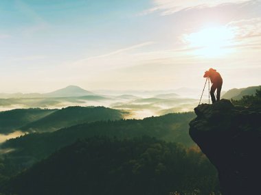 Eylem doğa fotoğrafçısı. Adam siluet bir puslu bulutların üstünde,
