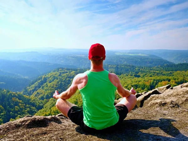 Hombre sentado en la cima de la montaña en pose de yoga. Ejercicio de yoga en el borde con una vista impresionante —  Fotos de Stock