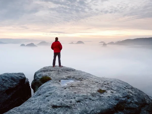 Escursionista uomo alla vetta della montagna. Splendido daybreak in autunno paesaggio nebbioso. Sole nascosto nelle nuvole — Foto Stock