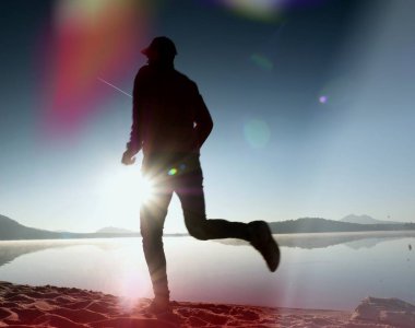  egzersiz ve göl kumsalda güneş doğarken uzanan bir adam. Sağlıklı bir yaşam tarzı. Yalnız genç fitness adam egzersiz sabah kumsalda