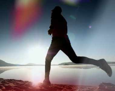 Kaçak ışık objektif. . Çalışan adam. Koş, sporcu adam kumlu bir plaj üzerinde gündoğumu sırasında koşu.