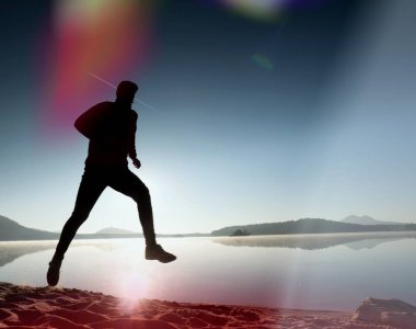 Kaçak ışık objektif. Adam siluet sabah güneş karşı sahilde egzersiz.