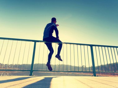 Runner siyah tayt içinde köprü yolu üzerinde uzanan vücut yapar. Güneş özetliyor vücut dostum.