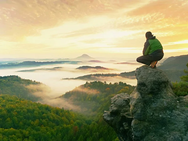 Hiker man take a rest on mountain peak. Man sit on sharp summit and enjoy spectacular view. — Stock Photo, Image