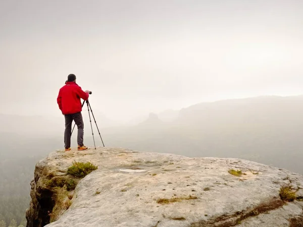 Fotograf denken über Bild auf Gipfel in den nebligen Bergen nach. Tal im dichten Nebel versteckt — Stockfoto