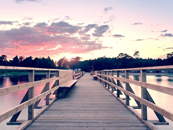 Ponte marítima longa na costa durante a manhã. Tempo frio com primeiros raios de sol no horizonte, água lisa. — Fotografia de Stock