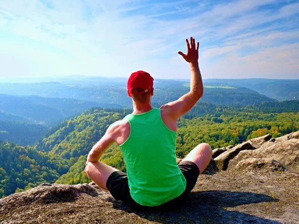 Karcsú test természetjáró zöld szingulett és fekete nadrág egy rock ül, élvezze a természetes táj. Nézd meg erdő völgybe — Stock Fotó