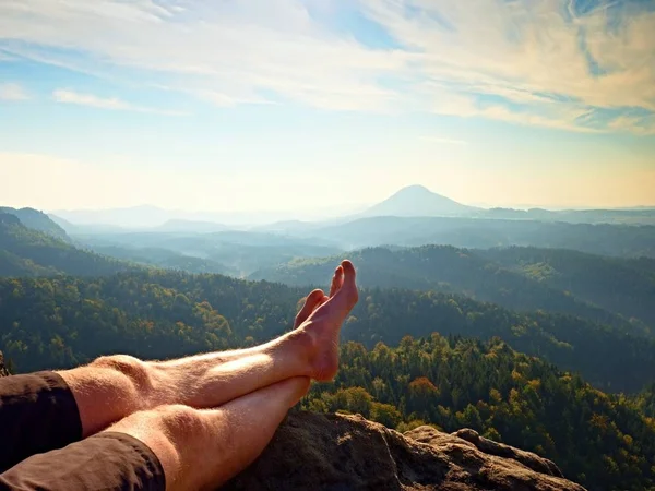 Piernas sudorosas masculinas desnudas en el pico de roca sobre el valle. El final de la caminata —  Fotos de Stock