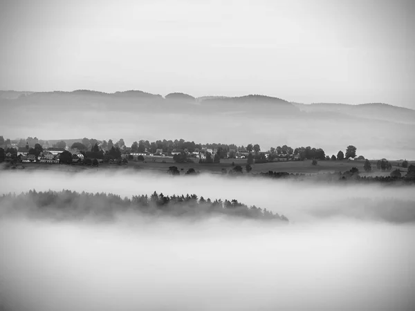 View into deep misty valley in Saxony. Sandstone peaks and rocky hills sticking up from thick fog. — Stock Photo, Image