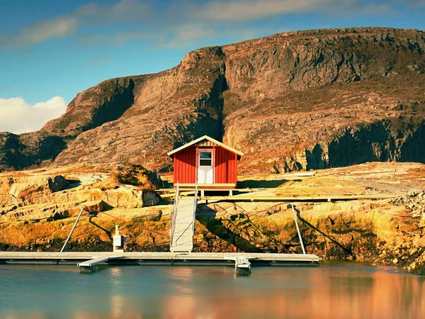 Casa de barco vermelho no cais, ilha rochosa, Noruega. Edifício branco vermelho tradicional no cais perto do mar — Fotografia de Stock