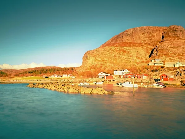 Kleines Fischerdorf auf einer Felseninsel im Nordmeer. Traditionelle rote und weiße Holzhäuser in der Nähe des Hafens — Stockfoto