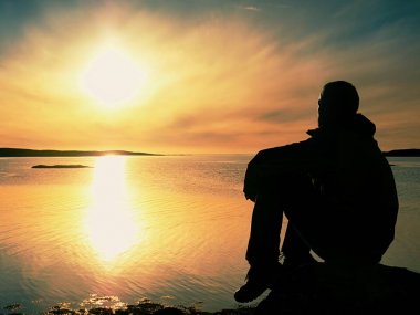 Gün batımında genç yolcusu adam. Uçurumdaki göl üzerinde oturan turist