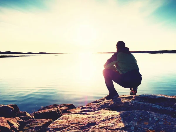 젊은 남자는 바다에 멋진 일몰을 보고 바위에 앉아. 도보 여행자 혼자 저녁을 즐길 수 — 스톡 사진