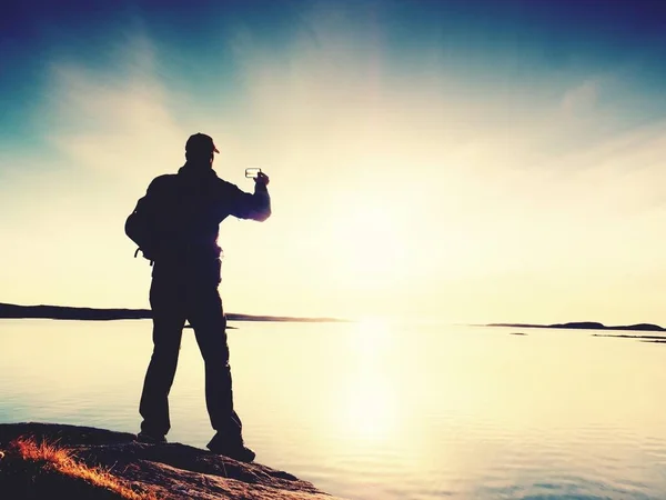 Alto turista prendendo selfie su cellulare contro vista panoramica del mare contro cielo serale. Specchio solare — Foto Stock