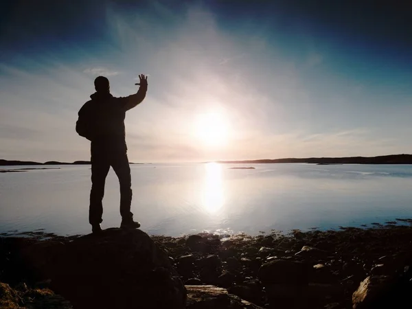 Silueta de hombre. Hermosa puesta de sol toque el mar en el horizonte, cielo azul claro. Senderista disfrutar del paisaje — Foto de Stock