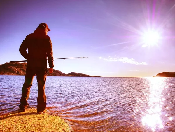 Ο δραστήριος άνδρας ψάρεμα στη θάλασσα από τη βραχώδη ακτή. Ψαράς έλεγχος ώθησης δόλωμα — Φωτογραφία Αρχείου