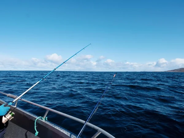 Fischerboot mit Angelruten, die im offenen Meer treiben. Hintergrund schöner Himmel. Sportfischen — Stockfoto