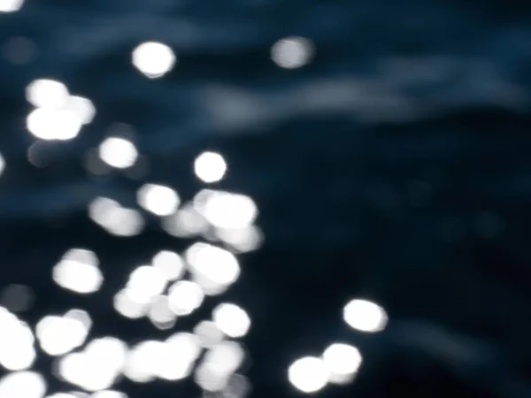 Heldere bruisend water in duisternis. Slowmotion, abstracte onscherpe achtergrond — Stockfoto