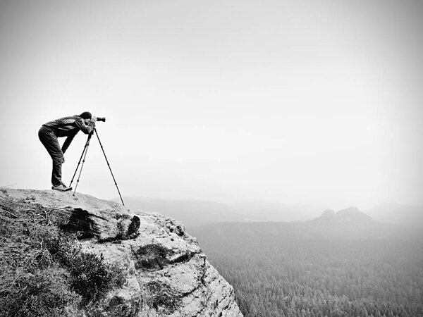 Wildlife photographer on mountain summit works. Man like to travel and photography, taking pictures
