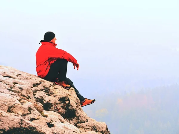 Denkende Menschen sitzen auf Felsen. Mann auf Aussichtspunkt des exponierten Gipfels beobachtet neblig weite Entfernung. — Stockfoto