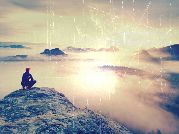 Абстрактный эффект. Турист сидит на вершине песчаника рок и смотреть в красочный туман и туман в утренней долине . — стоковое фото