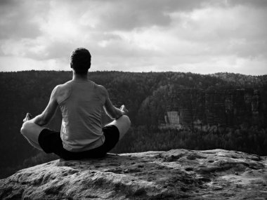 Adam içinde Lotus poz kayalık uçurum üzerinde meditasyon. Pratik Yoga taş kenarında sporcu 