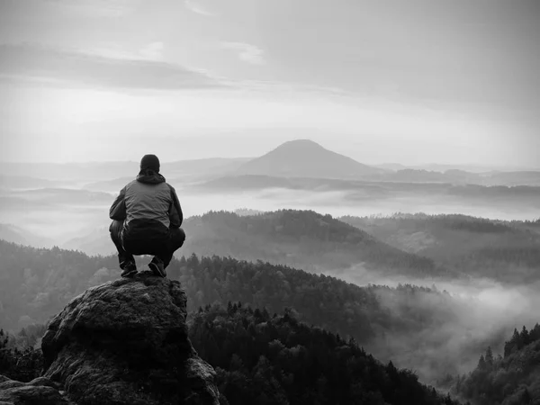 Man bo på rocky peak inom gryning och vaka över dimmiga landskap. — Stockfoto