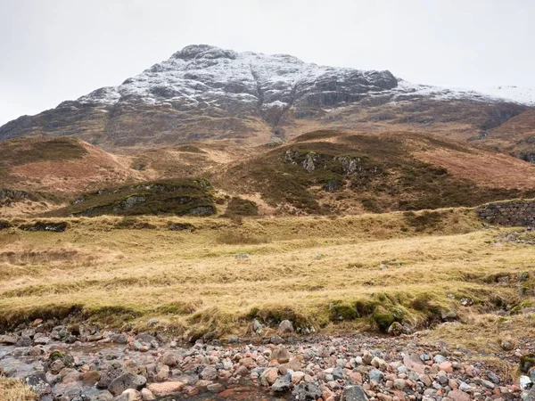 Dağ dere karla kaplı doruklarına içinde geçmiş. Alçak bulutlar ile karanlık gökyüzü. 