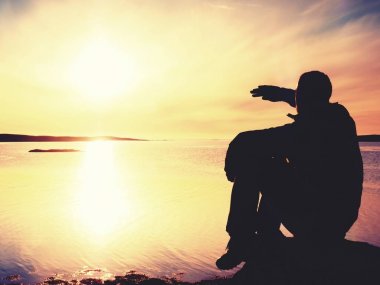 Yalnız adam uzun yürüyüşe çıkan kimse yalnız sahil ve günbatımı zevk üzerinde oturur. Okyanusa kayalık uçuruma görüntülemek