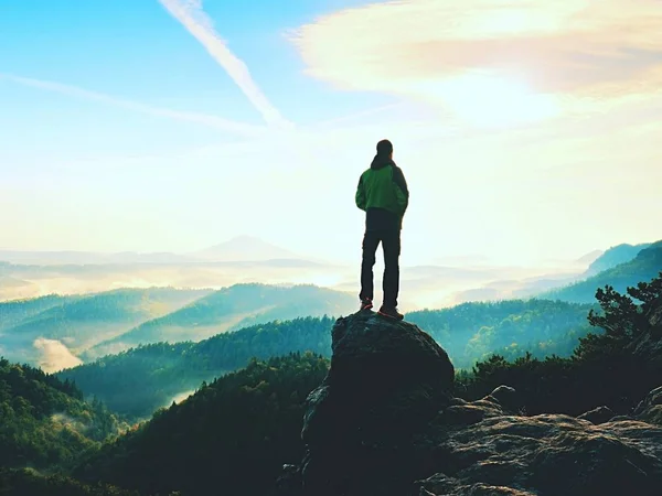 Hiker is standing on sandstone peak in rocky park and watching over misty and foggy morning valle — Stock Photo, Image