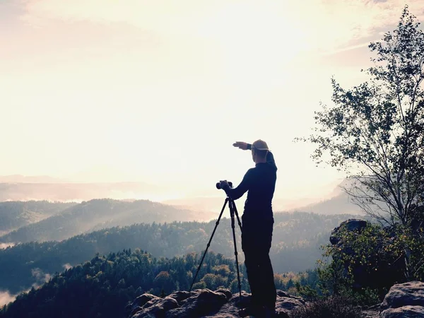 在悬崖上的摄影师。自然摄影师在岩石的山顶拍摄与镜子照相机的相片. — 图库照片
